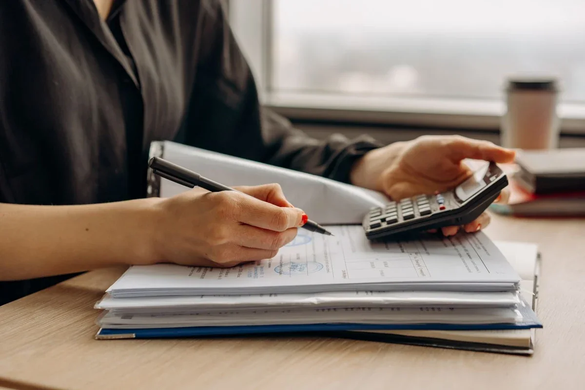 Person reviewing a notebook with a calculator at a desk