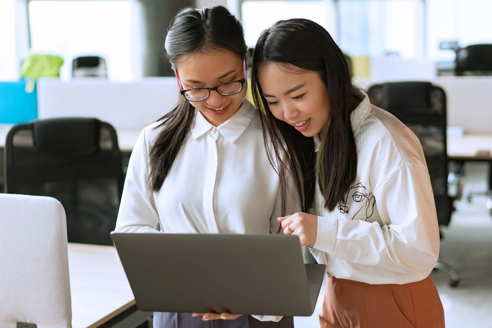 Two colleagues reviewing a laptop together in an office